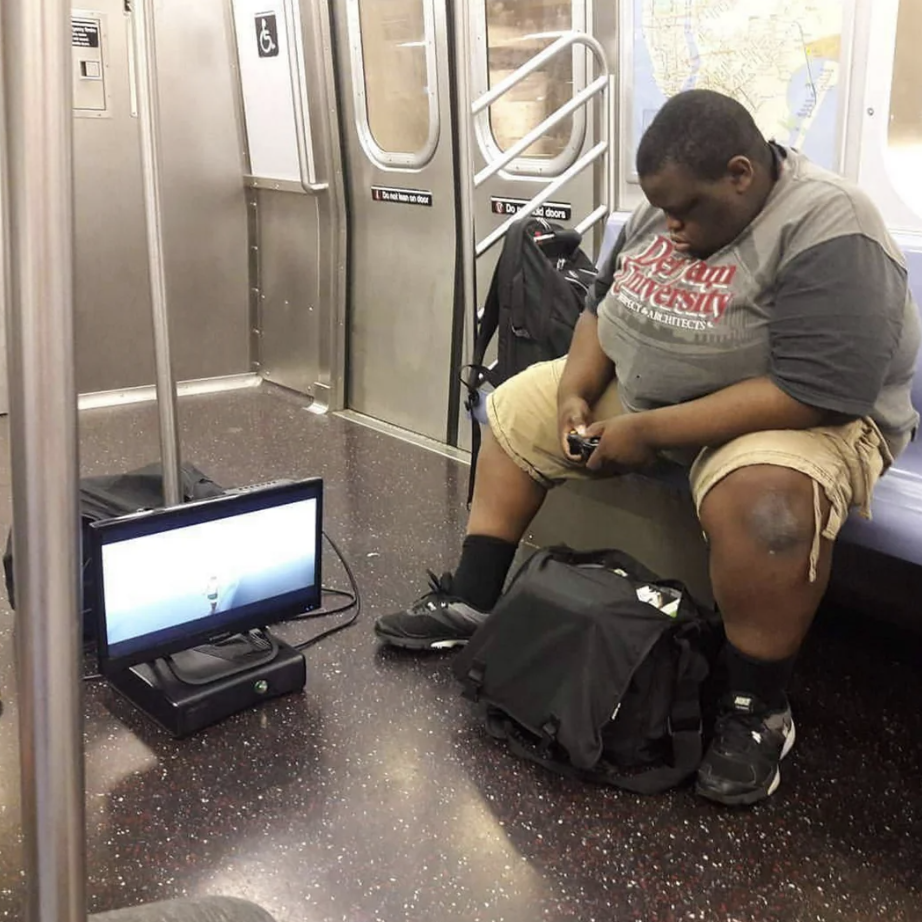 guy playing video games on subway - versity